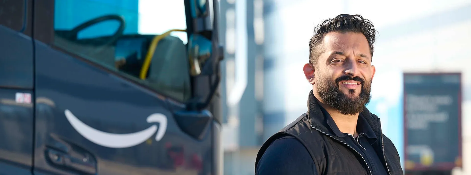 Smiling Amazon Freight Partners driver with a branded freight truck in the background