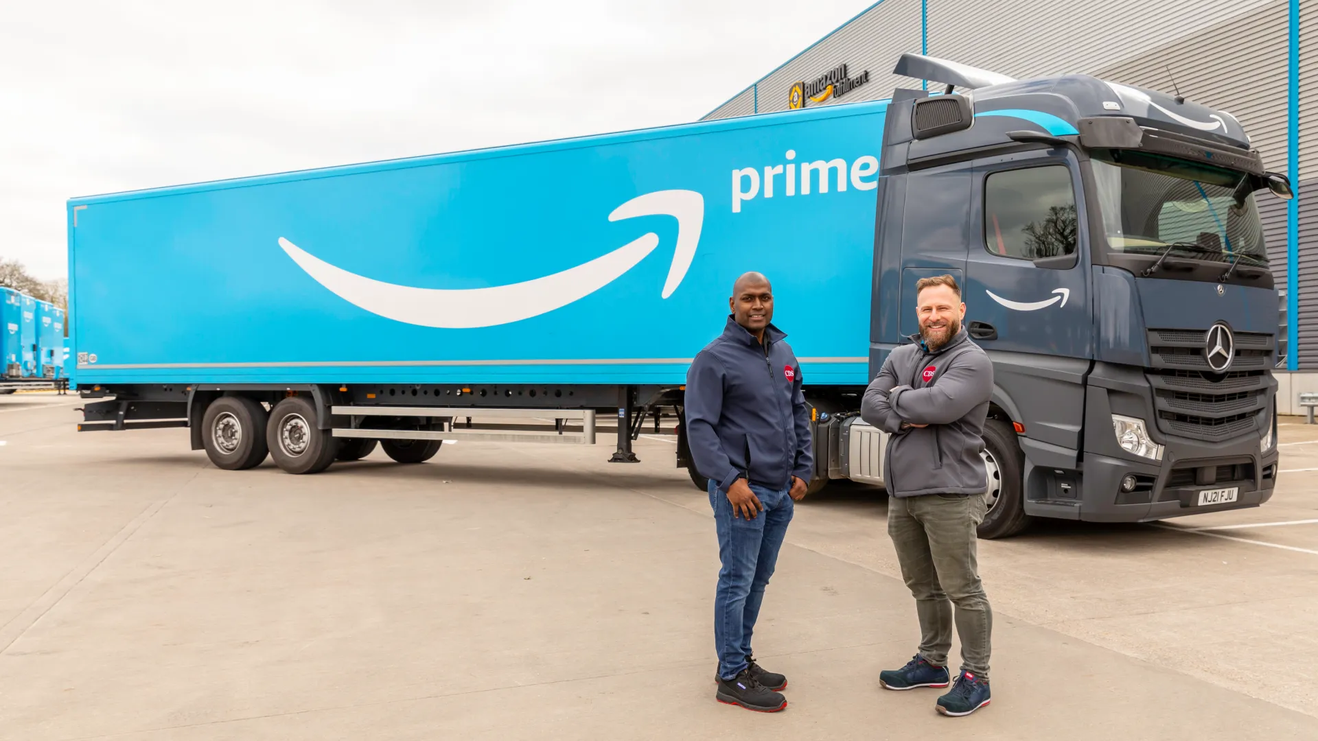 Two Amazon Freight Partners standing proudly in front of an Amazon Prime-branded truck