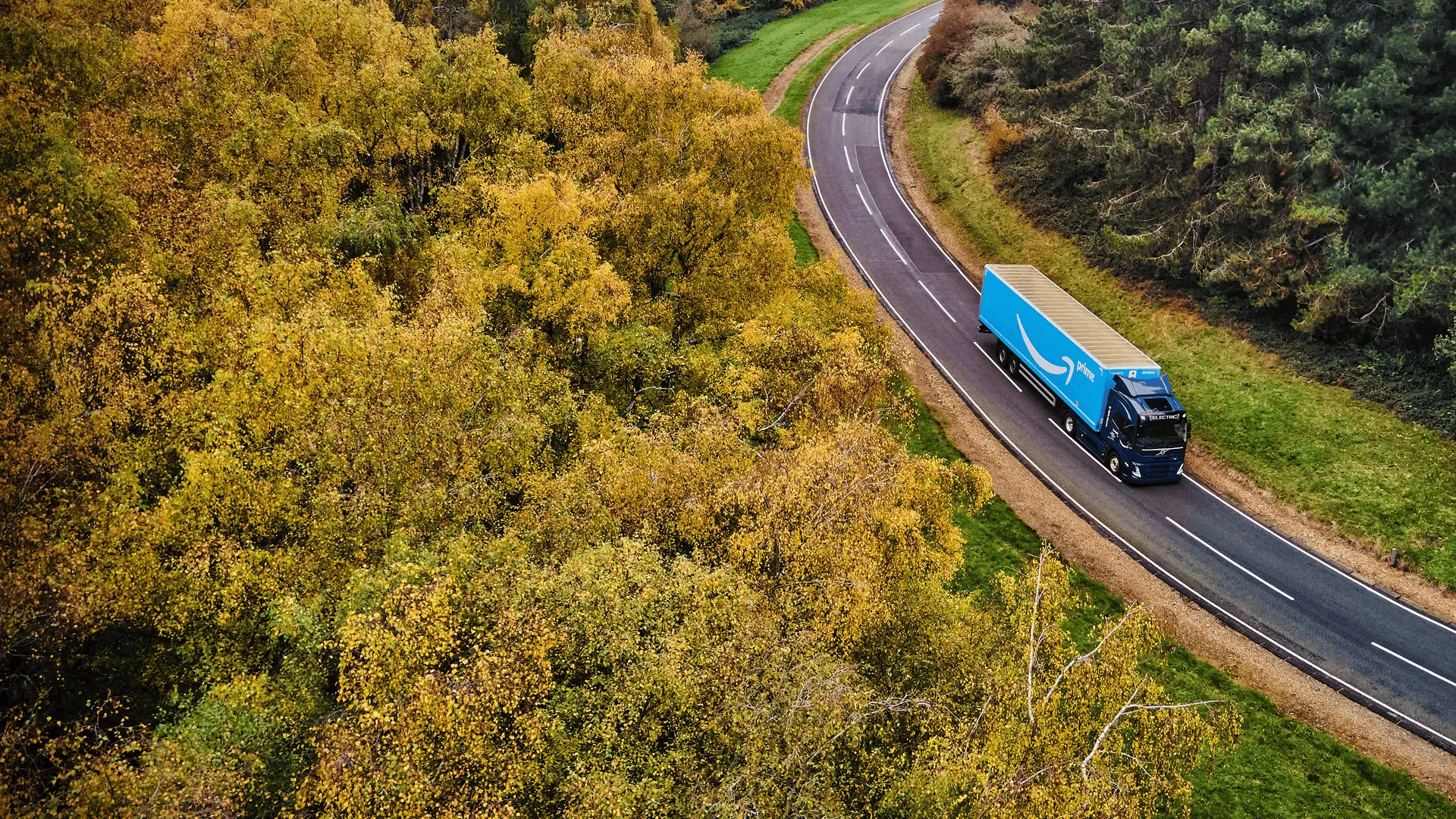 Amazon Freight Partners delivery truck cruising through a scenic tree-lined motorway